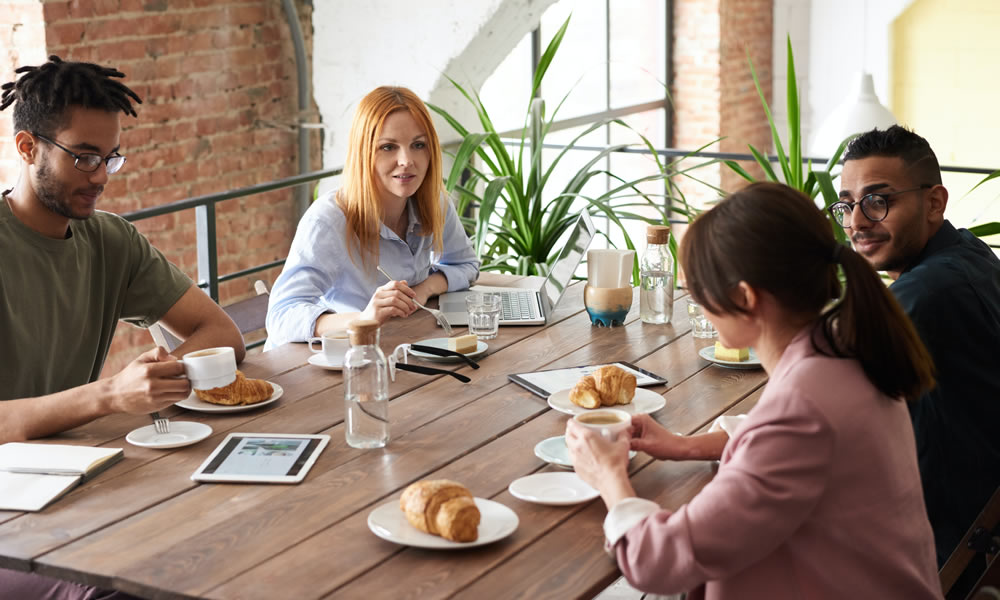 4 people having a breakfast meeting at a rustic wooden table